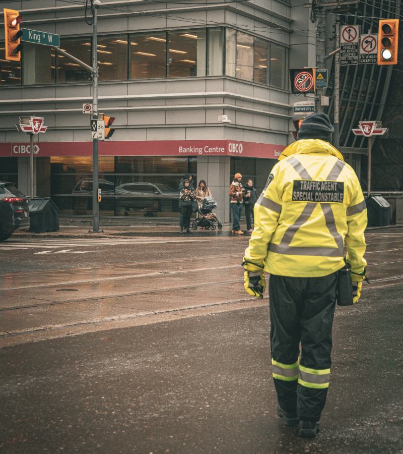 A traffic agent in a high-visibility jacket working an intersection on King Street West in Toronto
